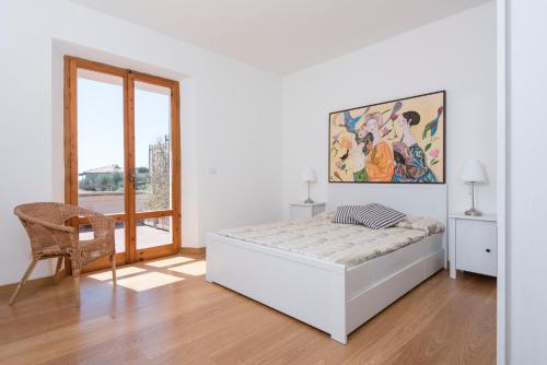 een witte kamer met een bed en een stoel bij Villa con Terrazza Vista Mare in Castiglione della Pescaia