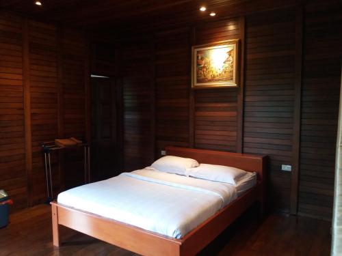 a bed in a room with wooden walls and a picture at Highland Resort & Nature Tours in Tomohon