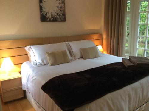 um quarto com uma grande cama branca e 2 candeeiros em Beechfield Cottages em Meopham