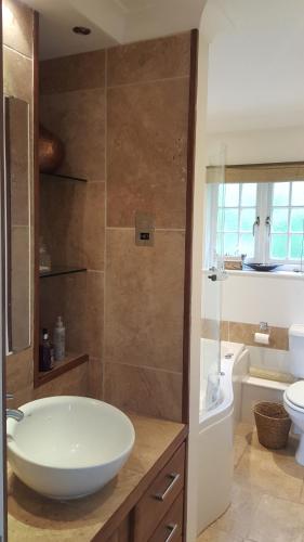 a bathroom with a sink and a tub and a toilet at Beechfield Cottages in Meopham