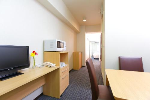 a hotel room with a television and a desk with chairs at FLEXSTAY INN Tokiwadai in Tokyo