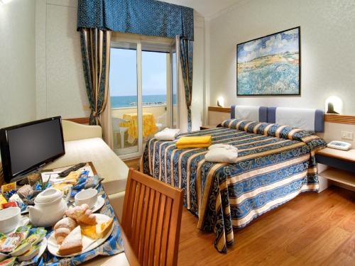 una habitación de hotel con 2 camas y una mesa con comida en Strand Hotel Colorado en Lido di Savio
