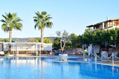 a large swimming pool with palm trees in front of a building at Villa Eugenia in Theológos