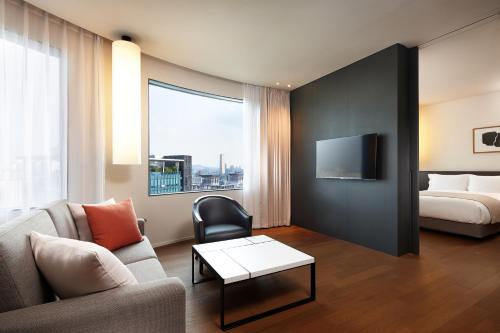 a living room with a couch and a bed at Shilla Stay Jeju Airport in Jeju