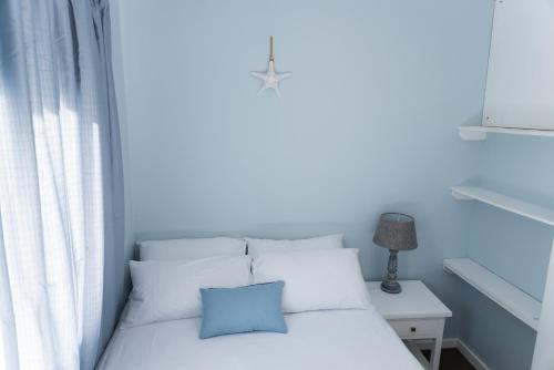 a bedroom with a white bed with a blue pillow at Whale View Self Catering Apartment in Hermanus