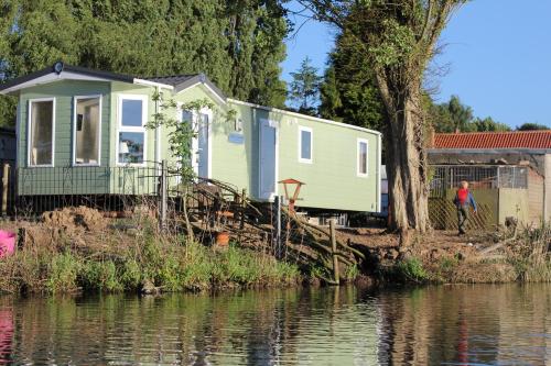 a tiny house sitting next to a body of water at Marshlands Lakeside Nature Retreat in Barton-upon-Humber