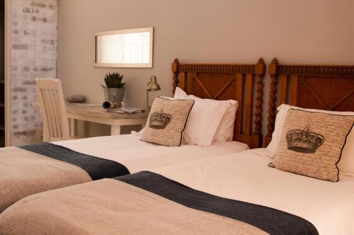 two beds in a bedroom with a table and a desk at Pumpkin Tree Guesthouse in Middelburg