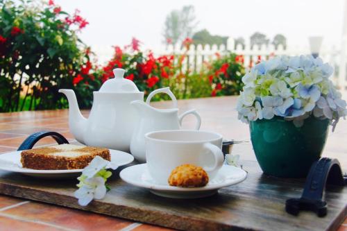 a table with a tea pot and a plate of cake at The Xanadu, Coonoor in Coonoor
