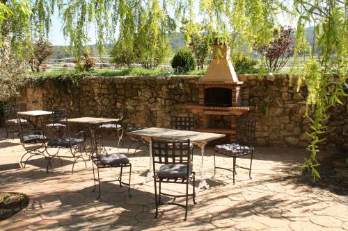a patio with tables and chairs and a fireplace at Cal Riba in Llacuna