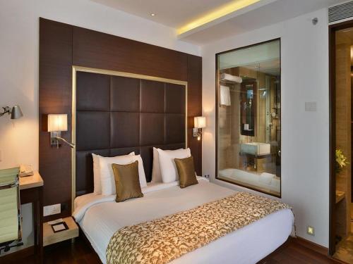 a bedroom with a large bed with a large headboard at Majestic Court Sarovar Portico in Navi Mumbai