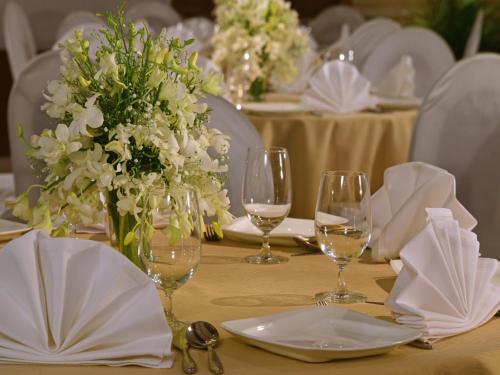 a table with wine glasses and white flowers on it at Majestic Court Sarovar Portico in Navi Mumbai