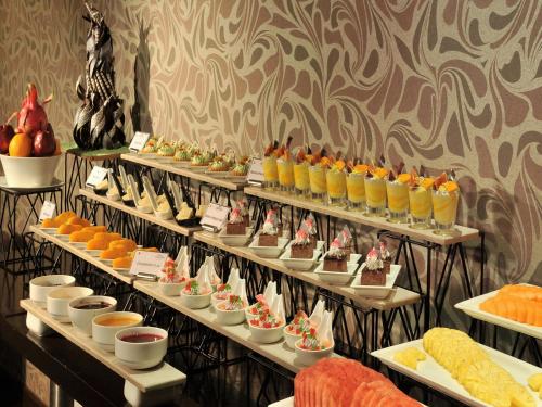 a bunch of shelves with desserts and oranges on them at Majestic Court Sarovar Portico in Navi Mumbai