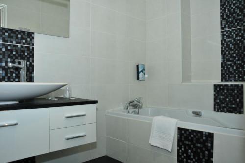 a white bathroom with a sink and a bath tub at Cit'Hotel Europeen in Angoulême
