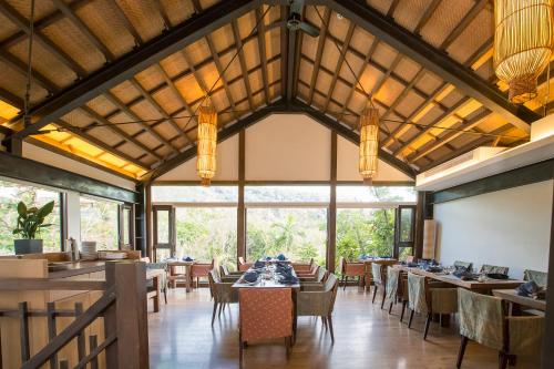 a dining room with tables and chairs and windows at Mudanwan Villa in Mudan