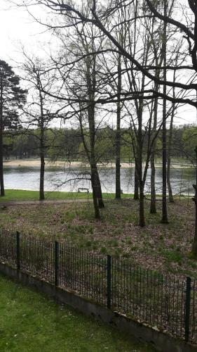 a fence with trees and a body of water at Hotel Daria Dworek Myśliwski in Łódź