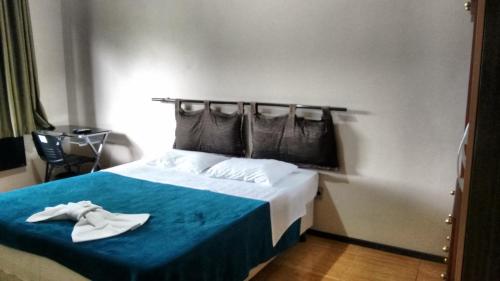 a hotel room with a bed with a blue blanket at Hotel Alpinus in Joinville