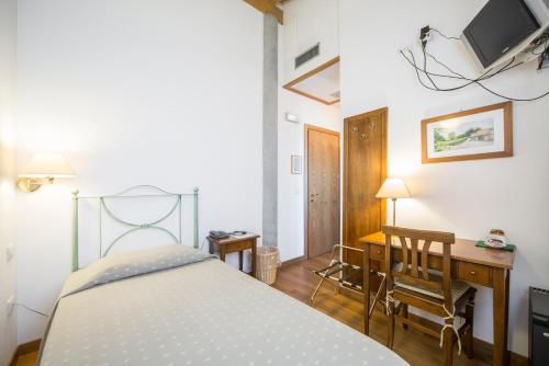 a bedroom with a bed and a desk with a tv at Agriturismo Gaggioli Borgo Delle Vigne in Zola Predosa