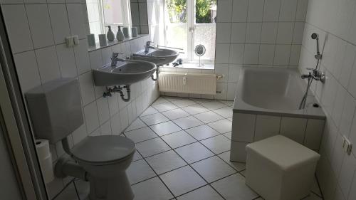La salle de bains est pourvue de 2 lavabos, de toilettes et d'une baignoire. dans l'établissement Altstadtloft Lüneburg, à Lunebourg