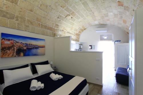 1 dormitorio con cama y pared de piedra en Il Viandante, en Polignano a Mare