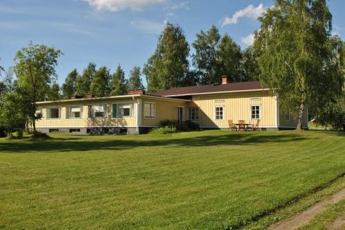 una casa amarilla con un gran campo verde delante de ella en Lomatila Ollila Bungalows, en Kerimäki