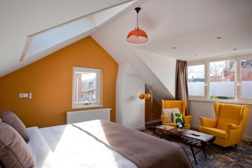 um quarto com uma cama e 2 cadeiras amarelas em B&B Ootmarsum em Ootmarsum