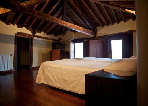 a bedroom with a large bed and two windows at Hospederia Porta Coeli in Sigüenza