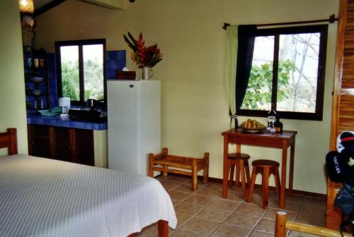 a bedroom with a bed and a kitchen with a refrigerator at Fidelito Ranch & Lodge in Tambor