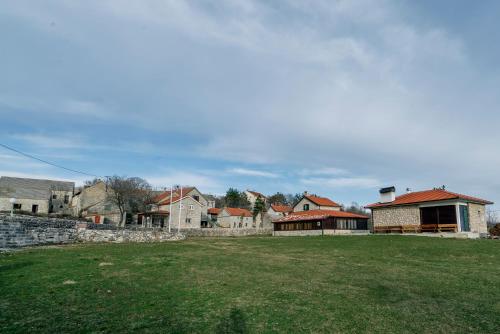 a group of buildings in a field with a yard at Apartman Studio Zdravko Eco Village in Imotski