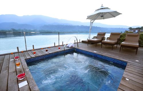 a swimming pool on a wooden deck with an umbrella at GANGA KINARE- A Riverside Boutique Resort, Rishikesh in Rishīkesh