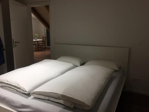 een bed met witte kussens in een kamer bij Ferienwohnung am Herzogspark in Regensburg