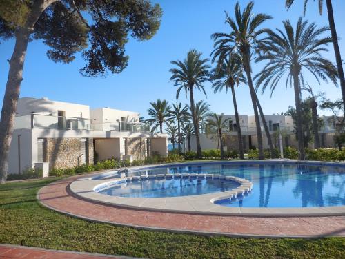 a swimming pool in front of a building with palm trees at Vila Paradis 18 in Villajoyosa
