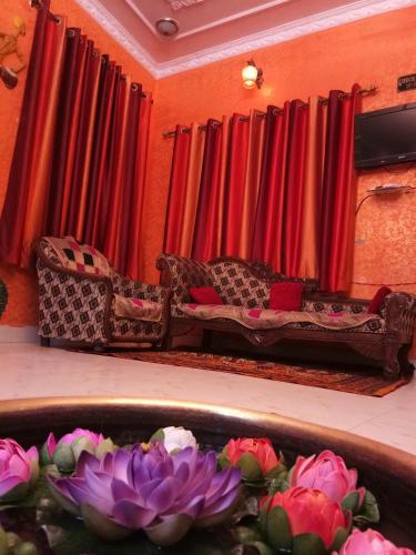 a living room with red curtains and a couch and flowers at Haveli Taragarh Palace in Būndi