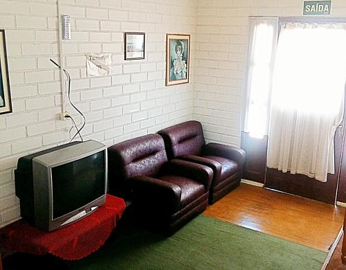 a living room with a couch and a tv at Pousada Alvorada in Cambará