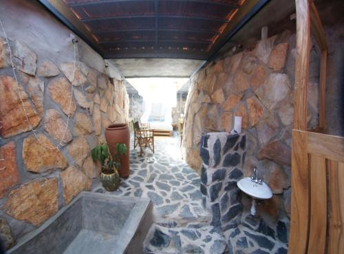 a stone walled bathroom with a tub and a sink at Yellow Haven Lodge in Kampala