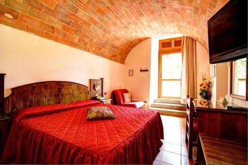 a bedroom with a red bed with a brick wall at Hotel Residence Villa Rioddi in Volterra