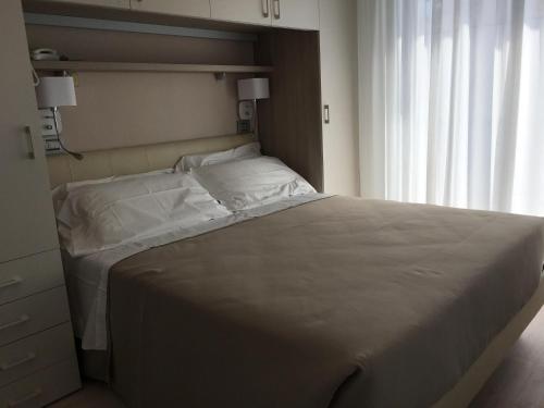 a large bed in a bedroom with a window at Hotel Novella in Misano Adriatico