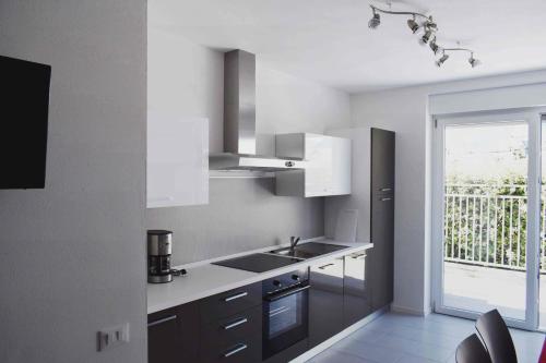 cocina con armarios blancos, fregadero y ventana en Residence Ambra, en Riva del Garda