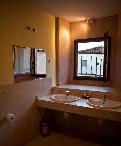 a bathroom with two sinks and a window at Hospederia Porta Coeli in Sigüenza