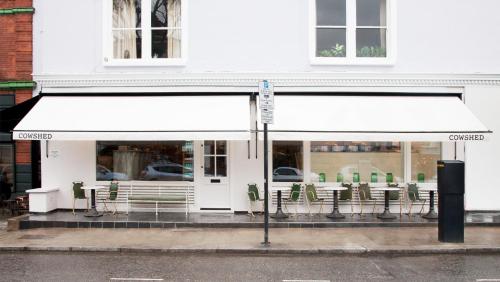 a restaurant with a white awning and tables and chairs at The Studio - Heart Of Primrose Hill in London