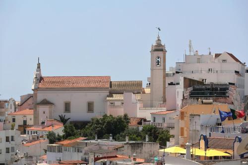 a group of buildings with a clock tower on a hill at Original 3 Bedroom Downtown in Albufeira