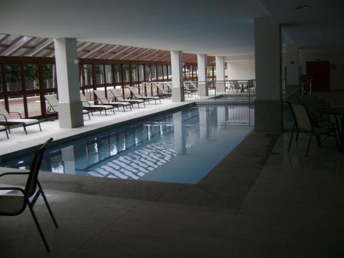 a swimming pool with chairs and tables in a building at Flat Particular Pedra Azul in Pedra Azul