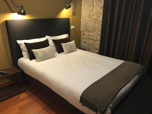 a bedroom with a large bed with white sheets and pillows at Quinta do Medronheiro Hotel Rural in Viseu