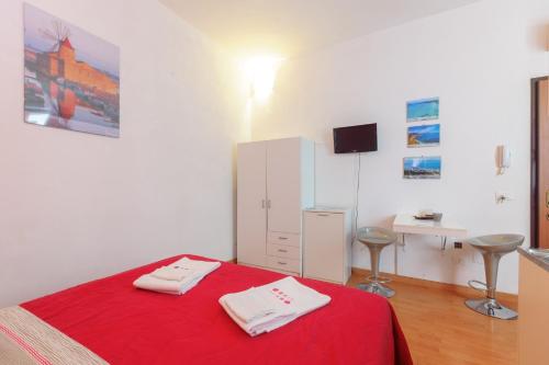 a bedroom with a red bed with two towels on it at Appartamenti Trapani Mare in Trapani