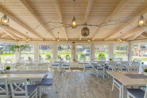 a dining room with tables and chairs and windows at Pensjonat Riwiera z widokiem na Zalew Wiślany in Krynica Morska