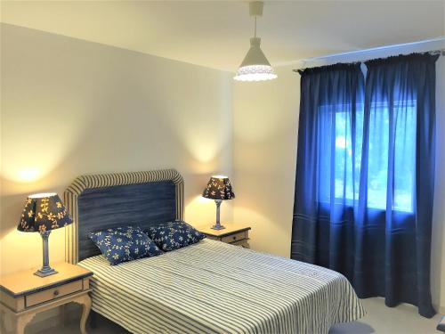 a bedroom with a bed with blue curtains and two lamps at Clube Nautilus Apartment in Porches