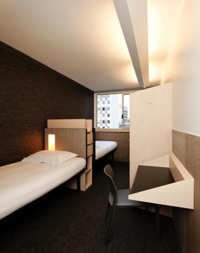 une chambre d'hôtel avec deux lits, un bureau et une fenêtre dans l'établissement FIAP Paris, à Paris