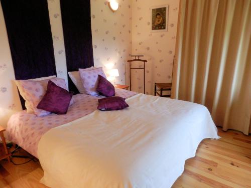 a bedroom with a large white bed with purple pillows at B&B Fromenteau in Ternant