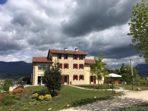 a large house on a hill with a cloudy sky at Agriturismo Lemire in San Pietro di Feletto