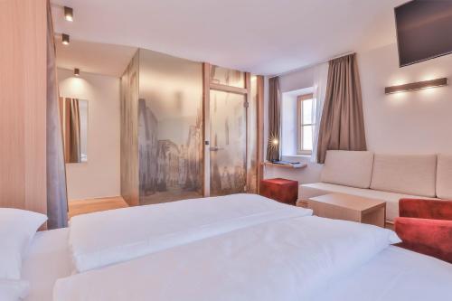 a hotel room with two beds and a couch at Belvenu Boutique Hotel in Glorenza