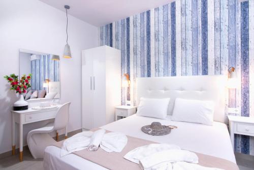a white bedroom with a bed and a desk at Estian Deluxe in Limenaria